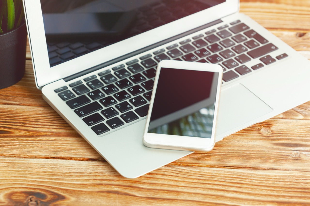 office desk with laptop smart phone and business office background.